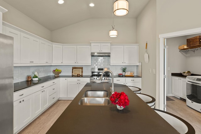 5718 N Vista Park Dr, Spokane, WA 99217 - kitchen featuring appliances with stainless steel finishes, dark countertops, light wood-style floors, white cabinetry, and vaulted ceiling