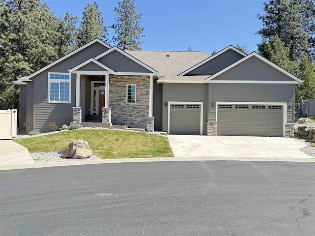 craftsman-style house with concrete driveway, an attached garage, stone siding, and a front yard