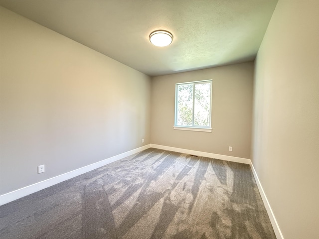spare room with dark colored carpet and baseboards