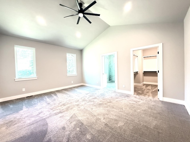 unfurnished bedroom with baseboards, ensuite bath, vaulted ceiling, a spacious closet, and carpet floors