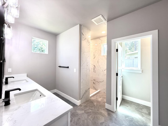bathroom with a marble finish shower, baseboards, and a sink