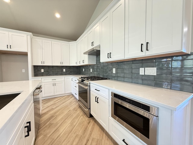 kitchen with stainless steel appliances, white cabinets, and light stone countertops
