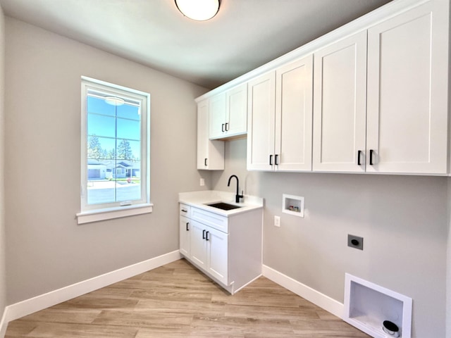 clothes washing area featuring a sink, electric dryer hookup, cabinet space, and baseboards