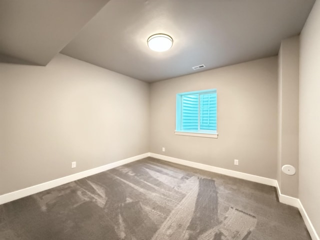 spare room with baseboards, visible vents, and dark carpet