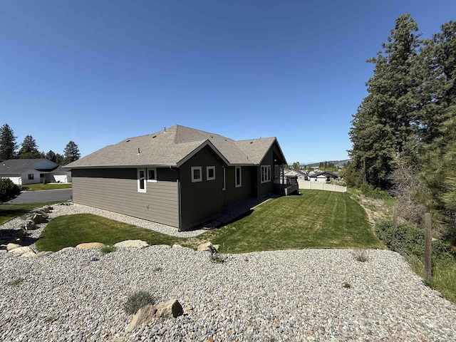 view of side of property featuring a yard and a shingled roof