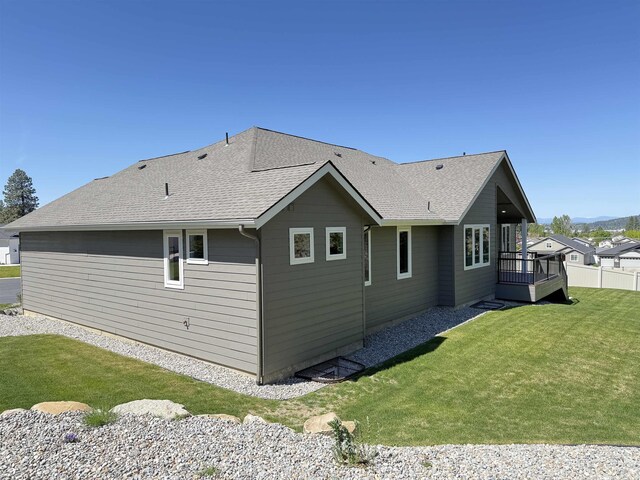 back of house with a yard, a deck, and a shingled roof