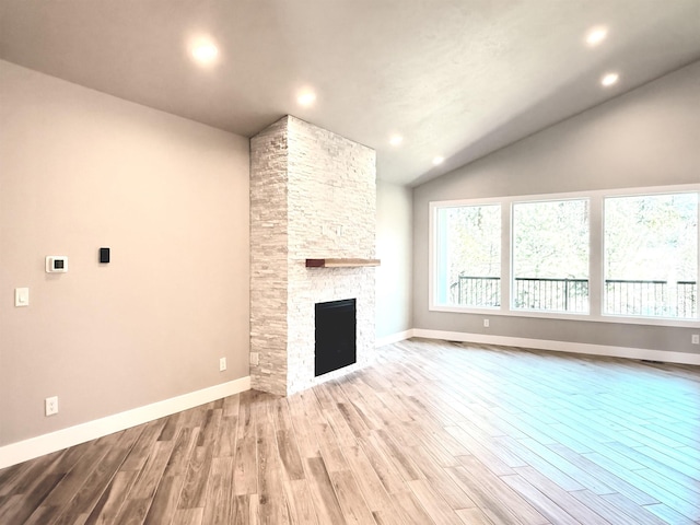 unfurnished living room featuring vaulted ceiling, wood finished floors, and baseboards