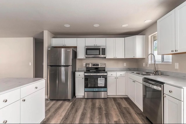 kitchen featuring a sink, white cabinetry, light countertops, appliances with stainless steel finishes, and dark wood-style floors