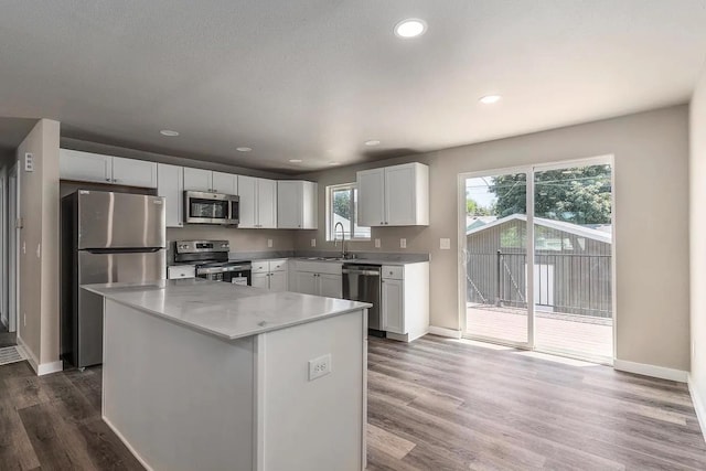 kitchen with baseboards, stainless steel appliances, white cabinets, and a sink