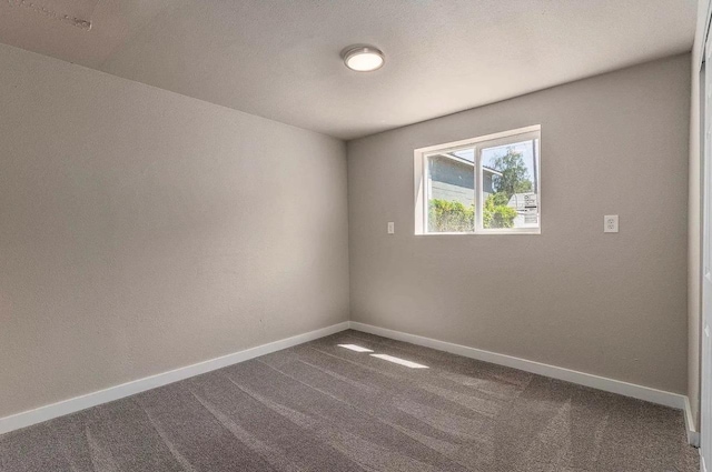 spare room with dark colored carpet and baseboards