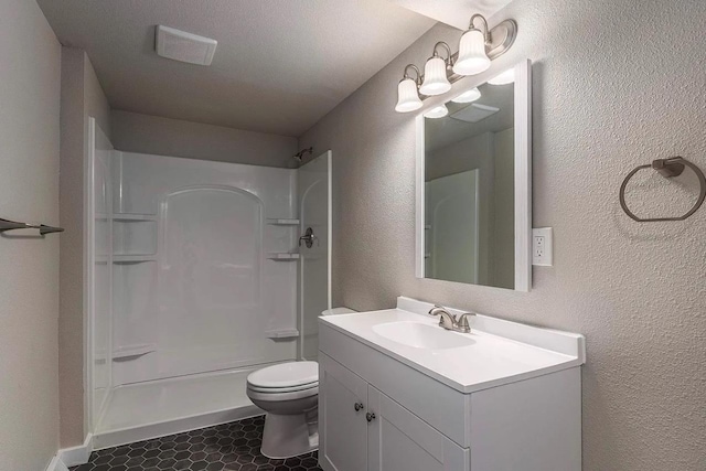 bathroom featuring toilet, a shower, vanity, and a textured wall