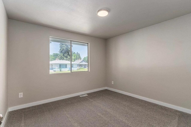 unfurnished room featuring baseboards, visible vents, and dark carpet
