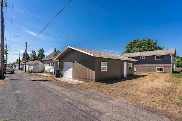 view of property exterior featuring a garage, an outbuilding, and driveway