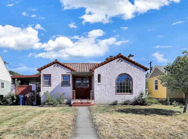 2424 W Fairview Ave, Spokane, WA 99205 - view of front of home with a tiled roof, a chimney, a front yard, and stucco siding