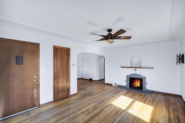 2424 W Fairview Ave, Spokane, WA 99205 - unfurnished living room featuring a lit fireplace, arched walkways, a ceiling fan, and wood finished floors