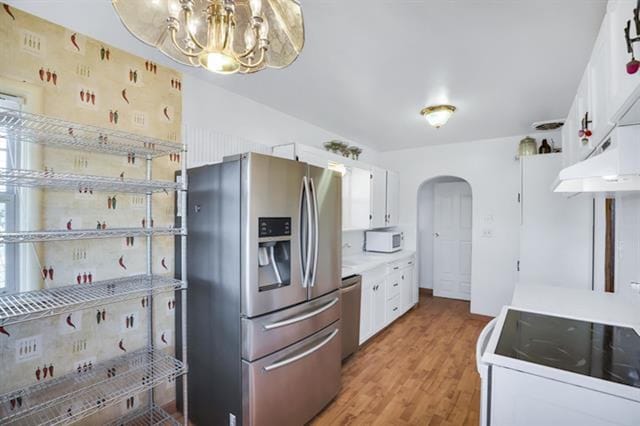 2424 W Fairview Ave, Spokane, WA 99205 - kitchen with appliances with stainless steel finishes, arched walkways, a chandelier, white cabinets, and light wood-style floors
