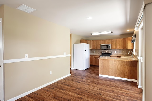 1605 W Kedlin Ln, Spokane, WA 99208 - kitchen featuring appliances with stainless steel finishes, dark wood-type flooring, a sink, decorative backsplash, and light countertops