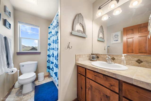 bathroom with toilet, baseboards, vanity, tile patterned floors, and backsplash