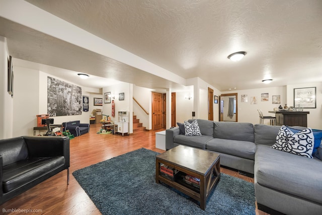 living area with stairs, wood finished floors, and a textured ceiling