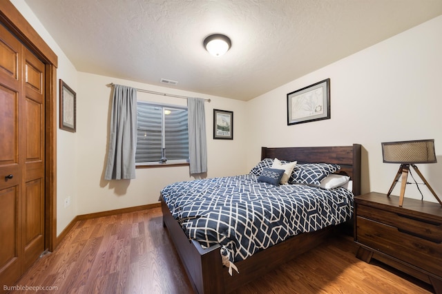 bedroom featuring wood finished floors, baseboards, and a textured ceiling