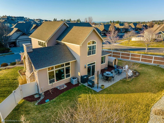 back of property featuring a residential view, a patio area, a shingled roof, central AC unit, and a gate