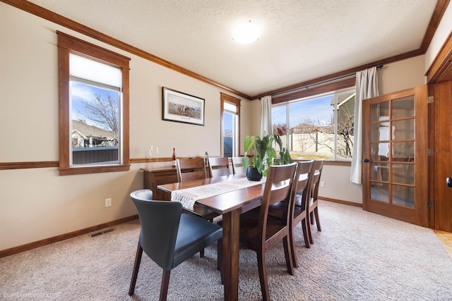 dining room with ornamental molding, a textured ceiling, baseboards, and light carpet