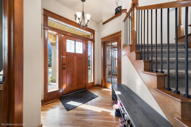 entryway with wood finished floors, stairs, a chandelier, and baseboards