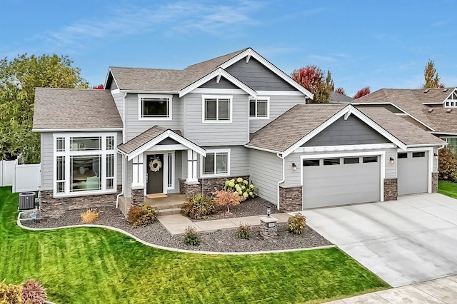 craftsman-style house featuring stone siding, a garage, driveway, and a shingled roof