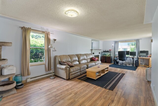 16813 E Valleyway Ave, Spokane Valley, WA 99037 - living area featuring baseboard heating, a lit fireplace, a textured ceiling, and wood finished floors