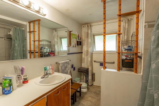 bathroom with tile walls, toilet, and vanity