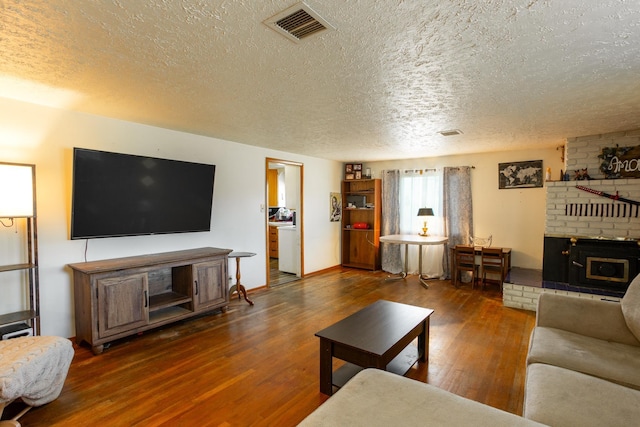 living area featuring a textured ceiling, a brick fireplace, and wood finished floors