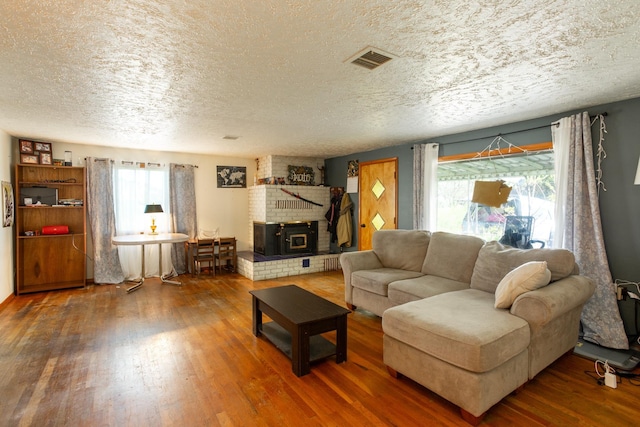 living area featuring a textured ceiling, wood finished floors, and a brick fireplace