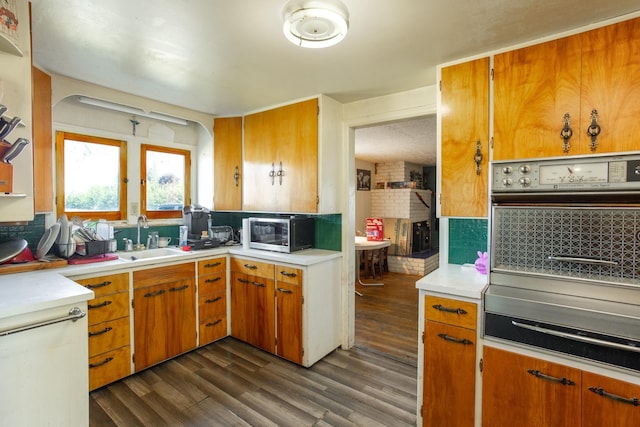 kitchen featuring a sink, stainless steel appliances, light countertops, and dark wood-style floors