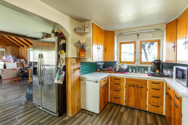 kitchen featuring appliances with stainless steel finishes, a sink, dark wood-style flooring, light countertops, and arched walkways