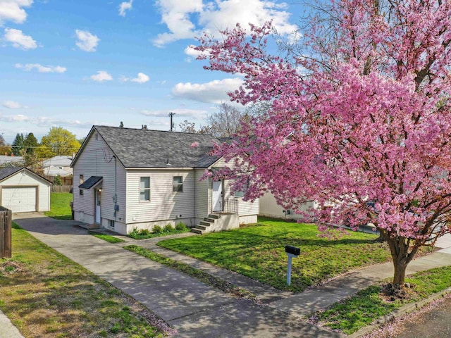 1734 N Stone St, Spokane, WA 99207 - view of front of property featuring driveway, an outdoor structure, a front yard, a detached garage, and roof with shingles