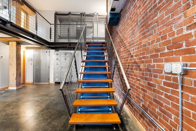 staircase featuring a towering ceiling, baseboards, and finished concrete flooring