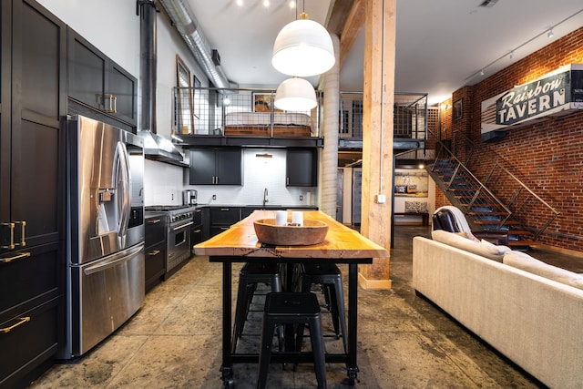 1016 W Railroad Ave Unit 202, Spokane, WA 99201 - kitchen with stainless steel appliances, a sink, brick wall, open floor plan, and dark cabinets