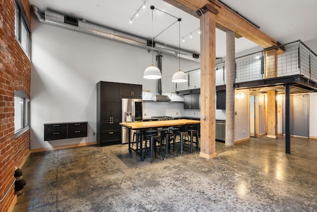 dining space featuring a towering ceiling, brick wall, baseboards, and decorative columns