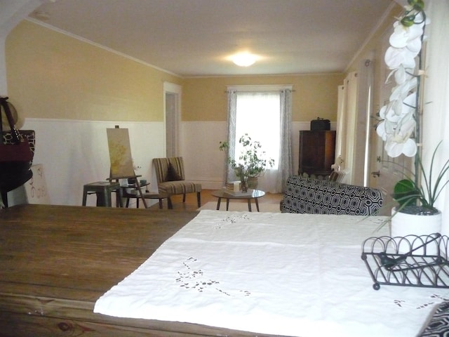 bedroom featuring a wainscoted wall and crown molding