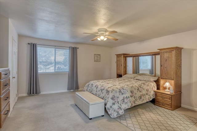 bedroom with light colored carpet, a ceiling fan, and baseboards