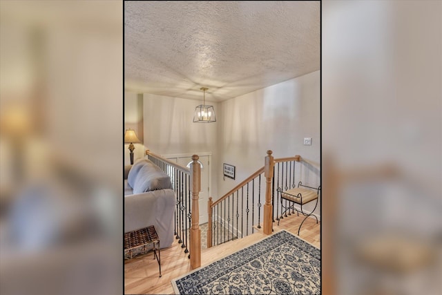 foyer entrance with a textured ceiling, wood finished floors, and a chandelier