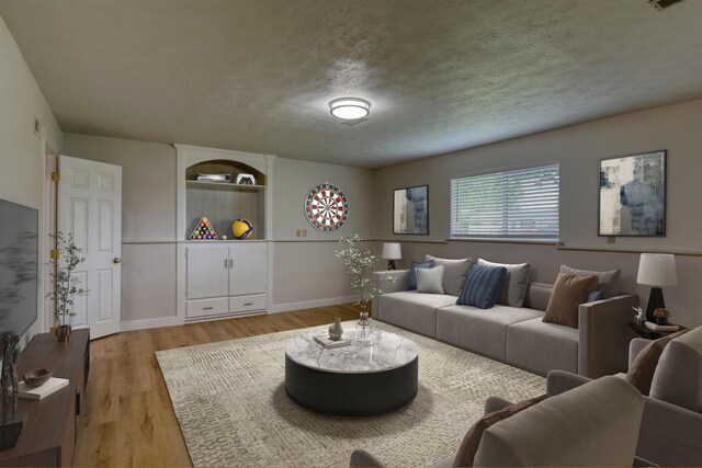 living area featuring light wood-style floors, baseboards, and a textured ceiling