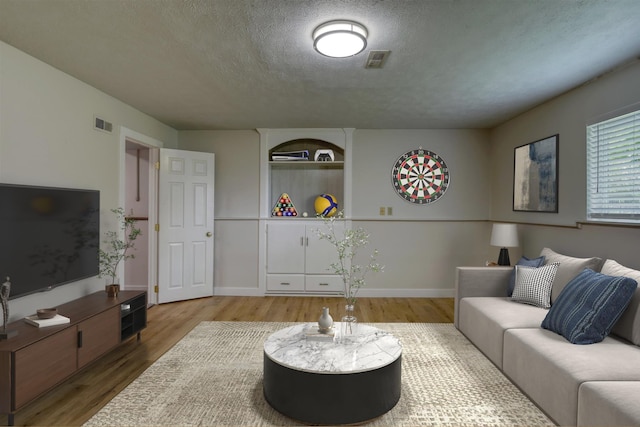 living room with wood finished floors, a textured ceiling, and baseboards