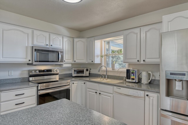 kitchen with appliances with stainless steel finishes, a sink, and white cabinets