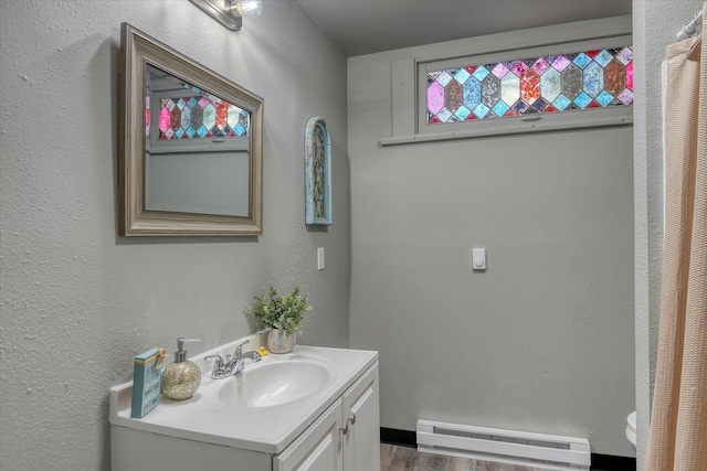 1121 W Knox Ave, Spokane, WA 99205 - bathroom with baseboard heating, vanity, wood finished floors, a textured wall, and toilet
