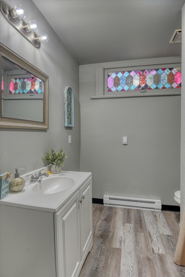 1121 W Knox Ave, Spokane, WA 99205 - bathroom with a baseboard radiator, vanity, wood finished floors, and toilet