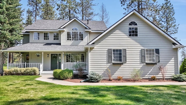 view of front of property featuring covered porch, a front lawn, and a shingled roof