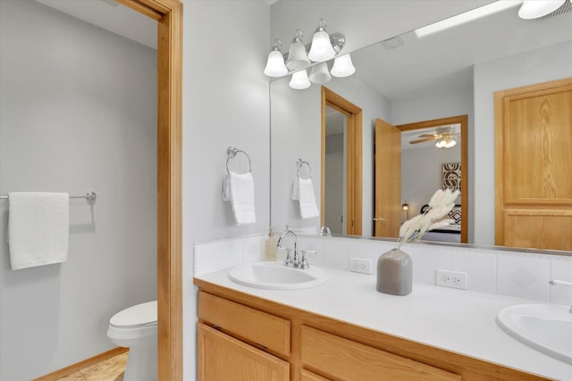 bathroom featuring double vanity, toilet, and ceiling fan