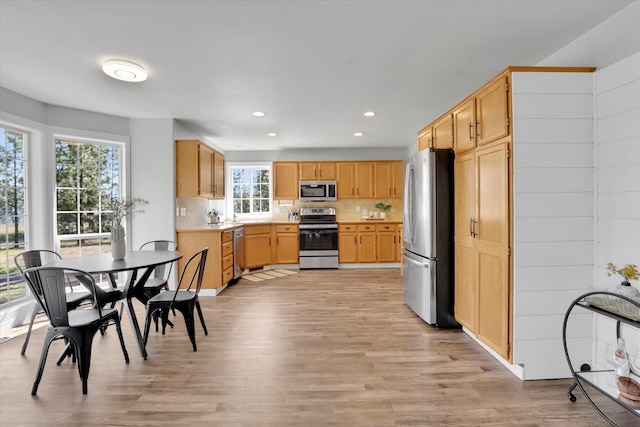 kitchen featuring appliances with stainless steel finishes, light wood-style floors, recessed lighting, decorative backsplash, and light countertops