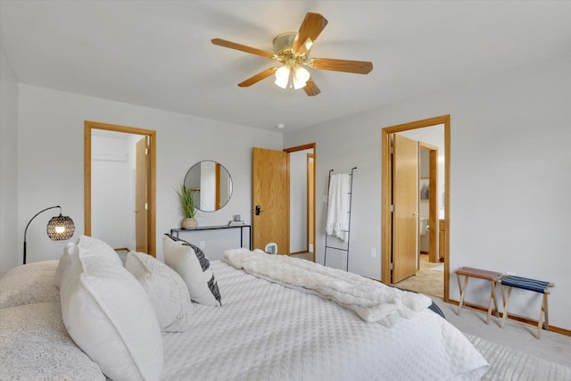 bedroom with light colored carpet, a ceiling fan, baseboards, and ensuite bath